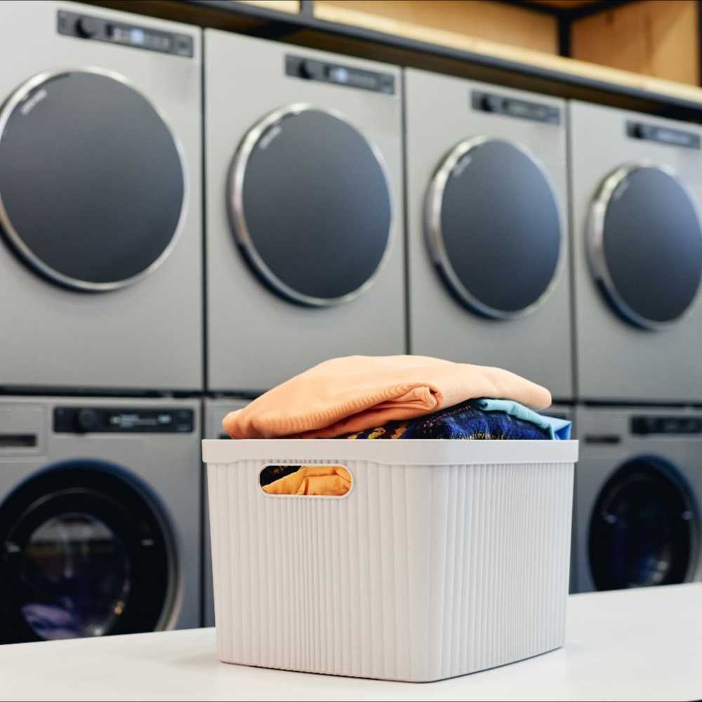 Neatly dried and folded laundry in front of modern dryers in a laundromat