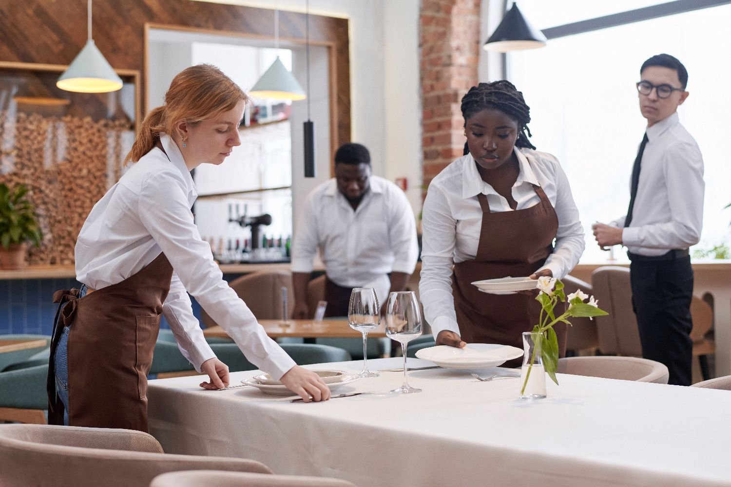 Restaurant staff setting tables with freshly laundered linens